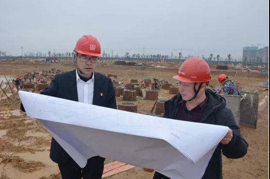 雨花城投集团和中海建筑的党员干部在工地看图纸。